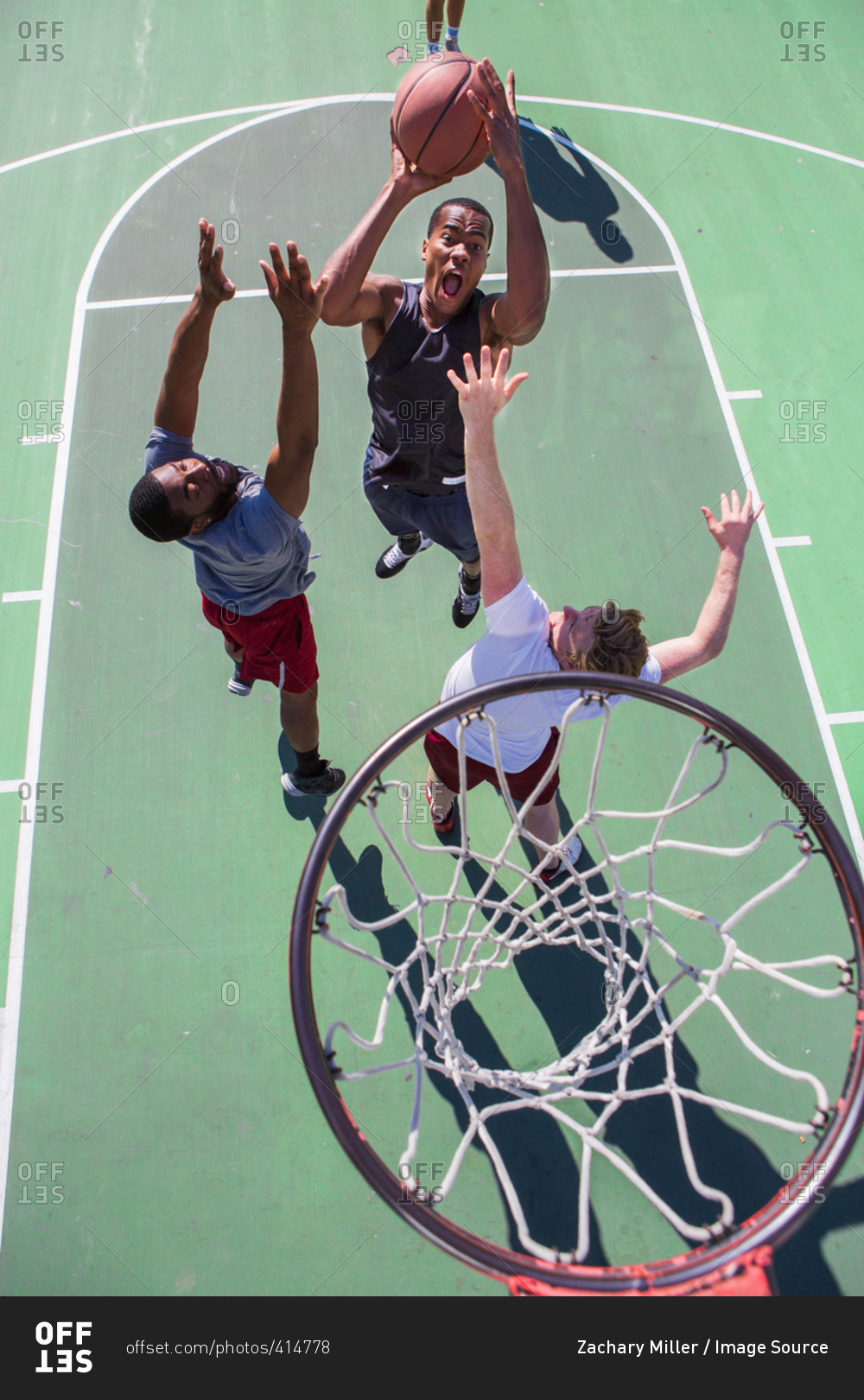 Group of male friends playing basketball on outdoor court, elevated view