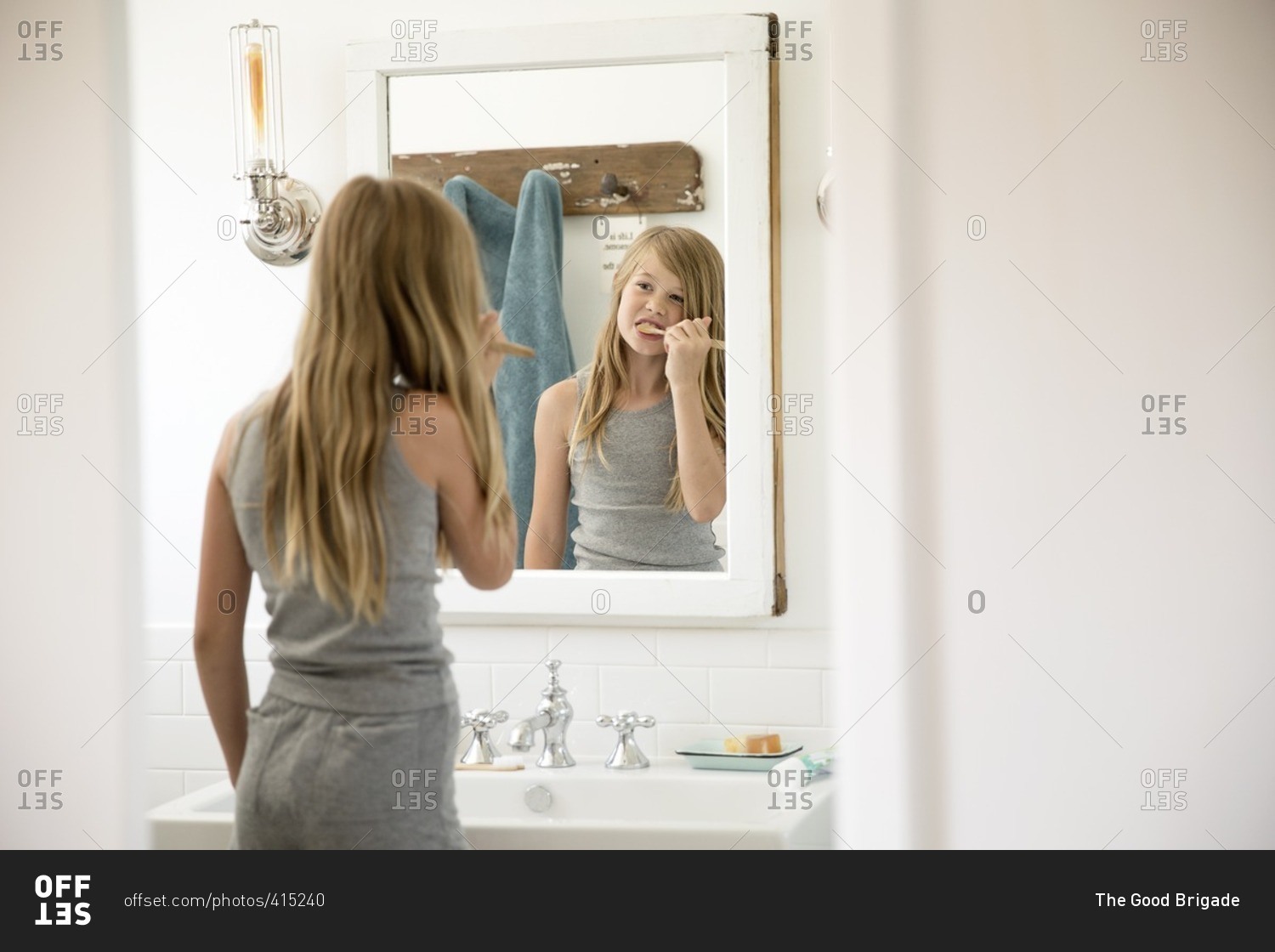 Little Girl Watching Herself Brush Her Teeth In A Bathroom