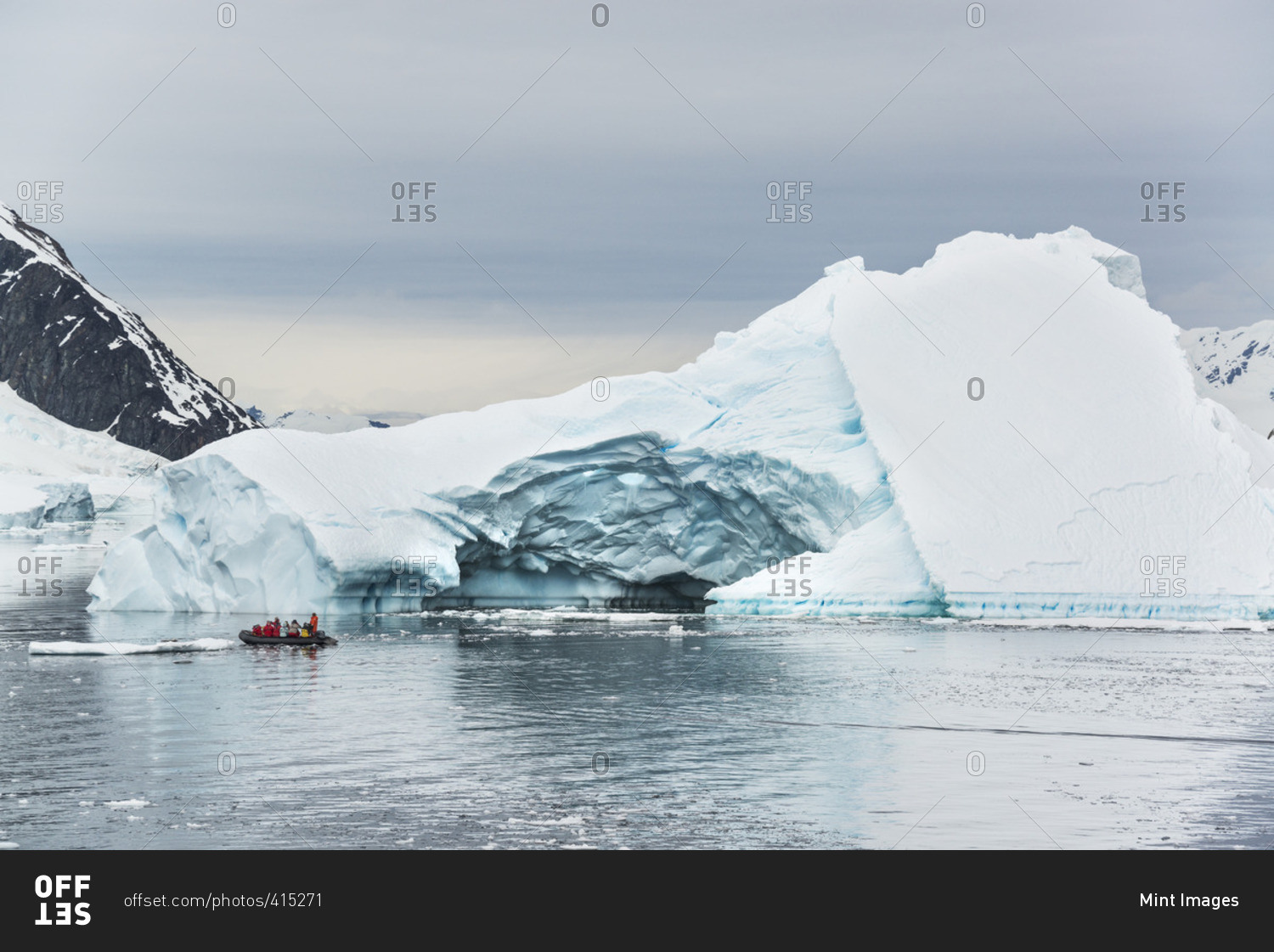 Group of people crossing the ocean in the Antarctic in a rubber boat, icebergs in the background