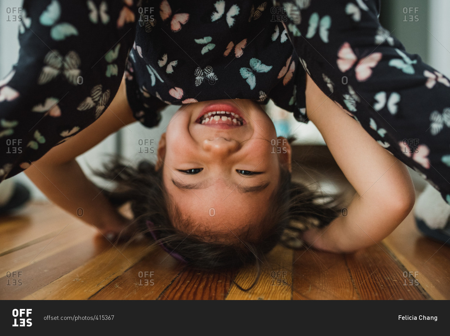 Little girl looking between her legs at the camera and smiling