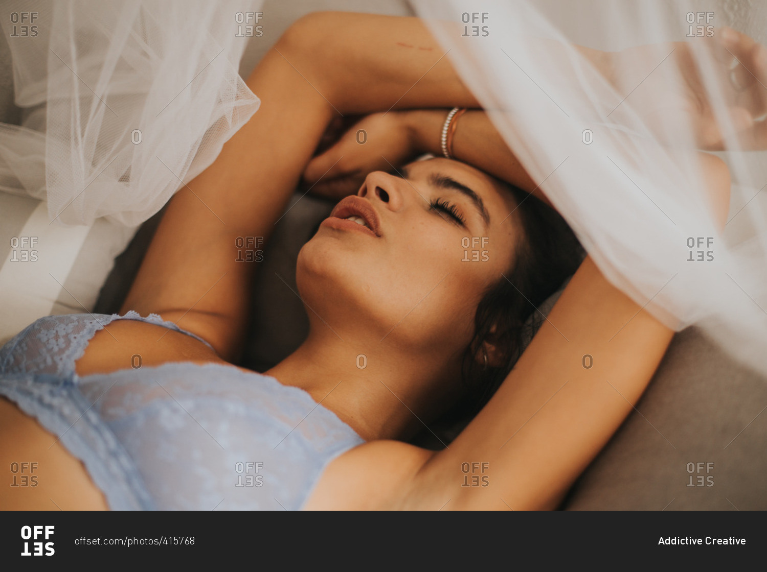 Sexy woman on bed in bra stock photo - OFFSET