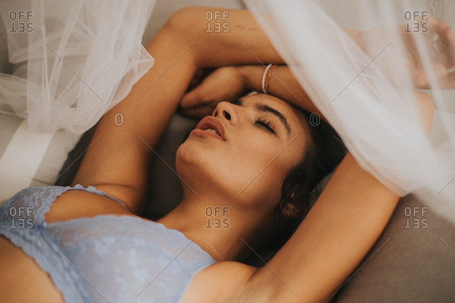 Sexy woman on bed in bra stock photo - OFFSET