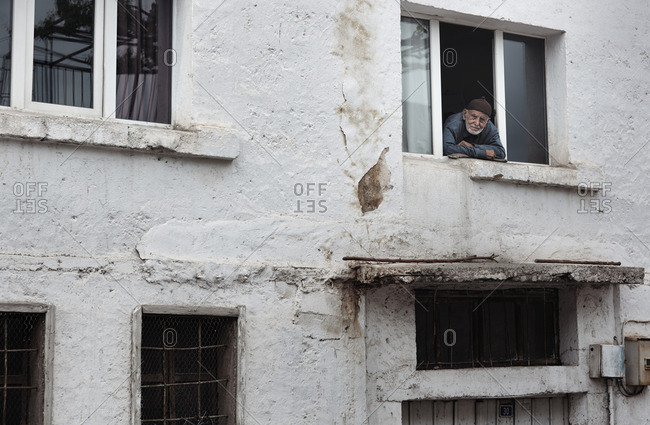 Cappadocia, Turkey - May 06, 2014: Senior Turkish man looking at camera through window