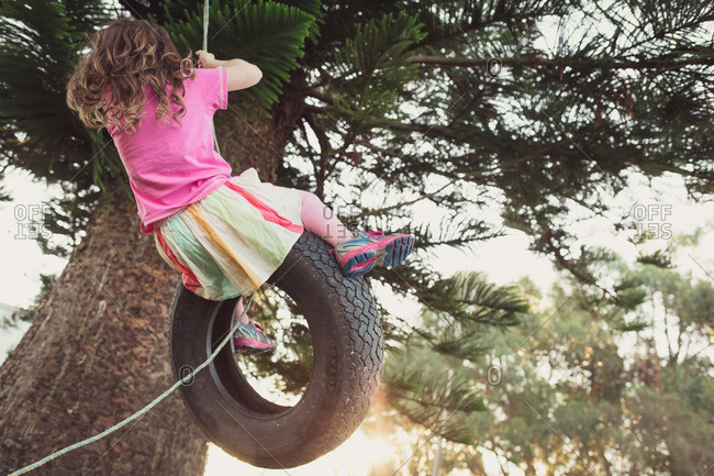 Girl Swinging High On Tire Swing From Tree Stock Photo Offset