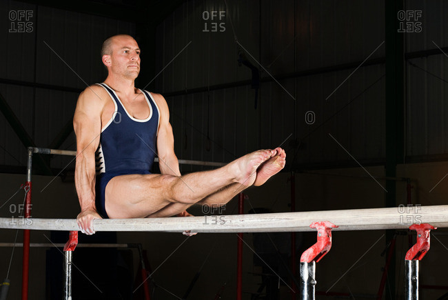 Man exercising in gymnasium, using parallel bars, in L-sit hold stock photo