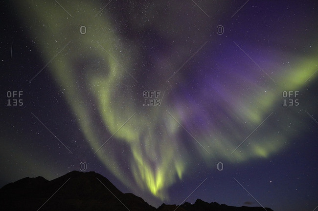 Aurora borealis in the night sky over mountains in Greenland
