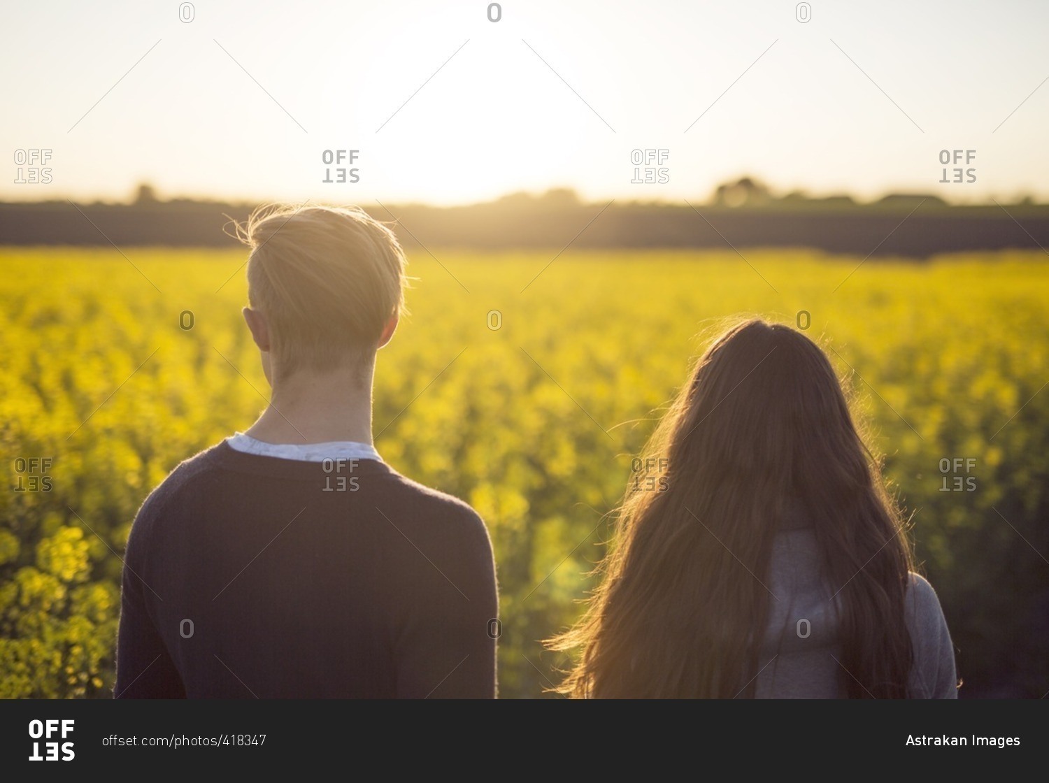 Two teens looking out at a country field at sunset