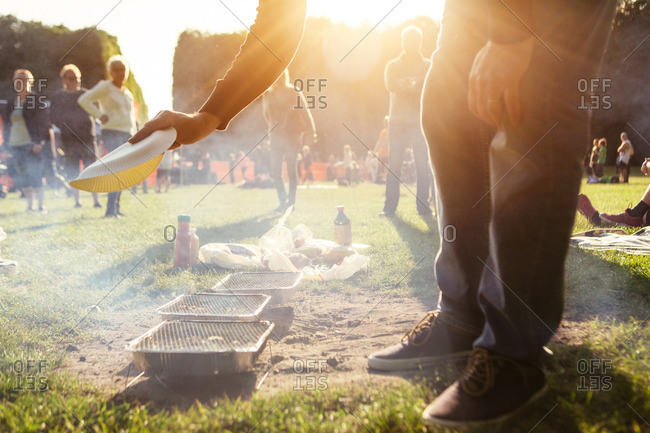 Man fanning smoke from disposable grill