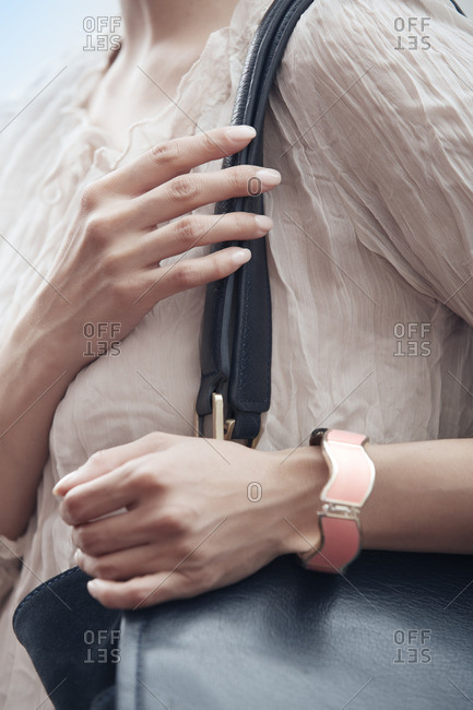 Woman holding a handbag and wearing a bangle on her wrist