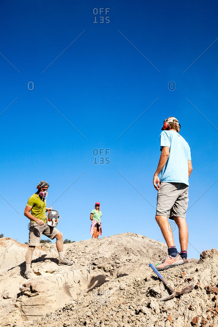 Kaiparowits, Utah, USA - September 20, 2015: Paleontologist with a rock saw in the field with other field workers looking on while excavating a site in Utah's Kaiparowits Plateau