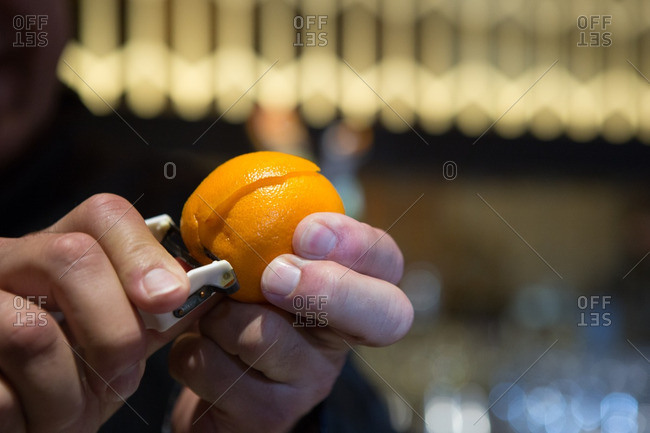 Bartender peeling rind from orange