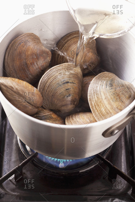Pour white wine onto clams