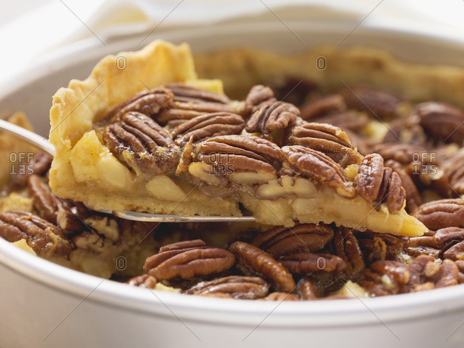 Pecan and apple pie in pie dish, one piece on cake slice