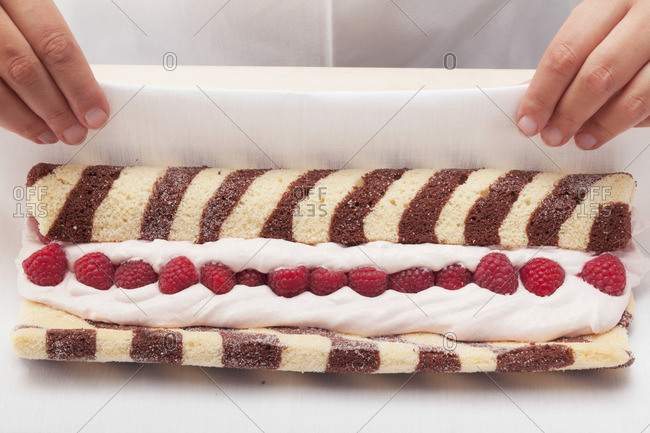 Black and white sponge roll with a raspberry filling being made