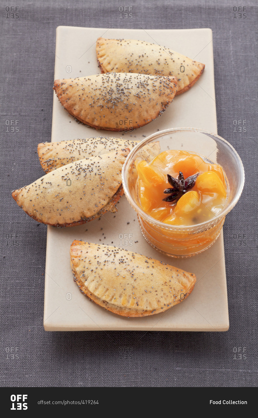 Sweet poppy seed pierogi (steamed dough parcels) with orange dip on an oblong plate
