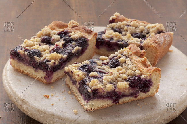 Three slices of blueberry crumble cake on a stone platter