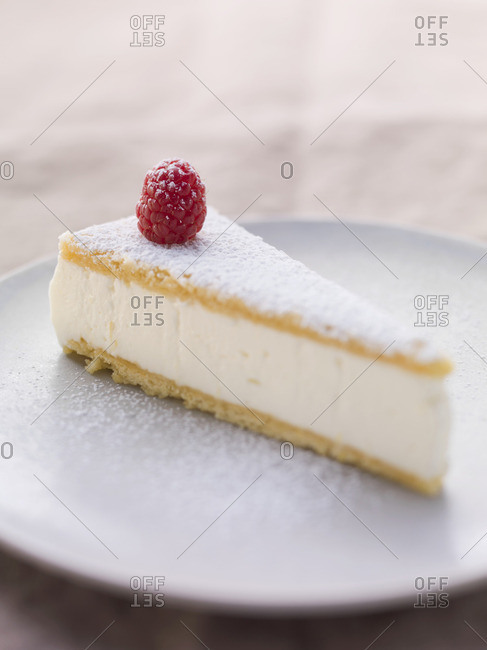 A slice of creamy cheese cake with icing sugar