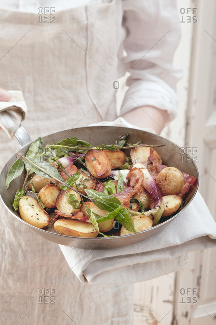 Potatoes and spring onions with herbs in a pan