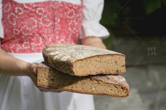 Woman in traditional costume holding coarse rye bread