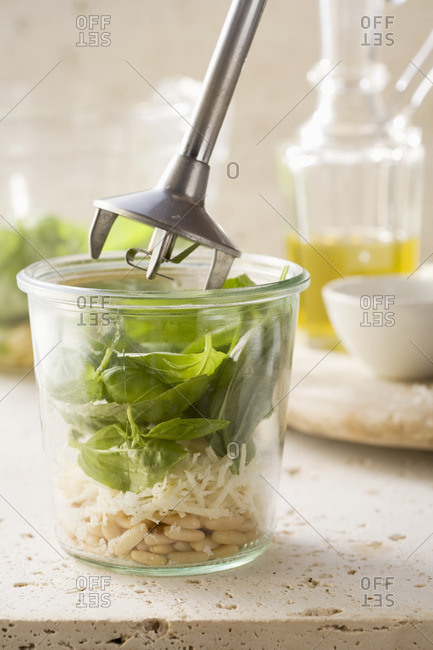 Basil, Parmesan and pine nuts being mixed with a hand mixer