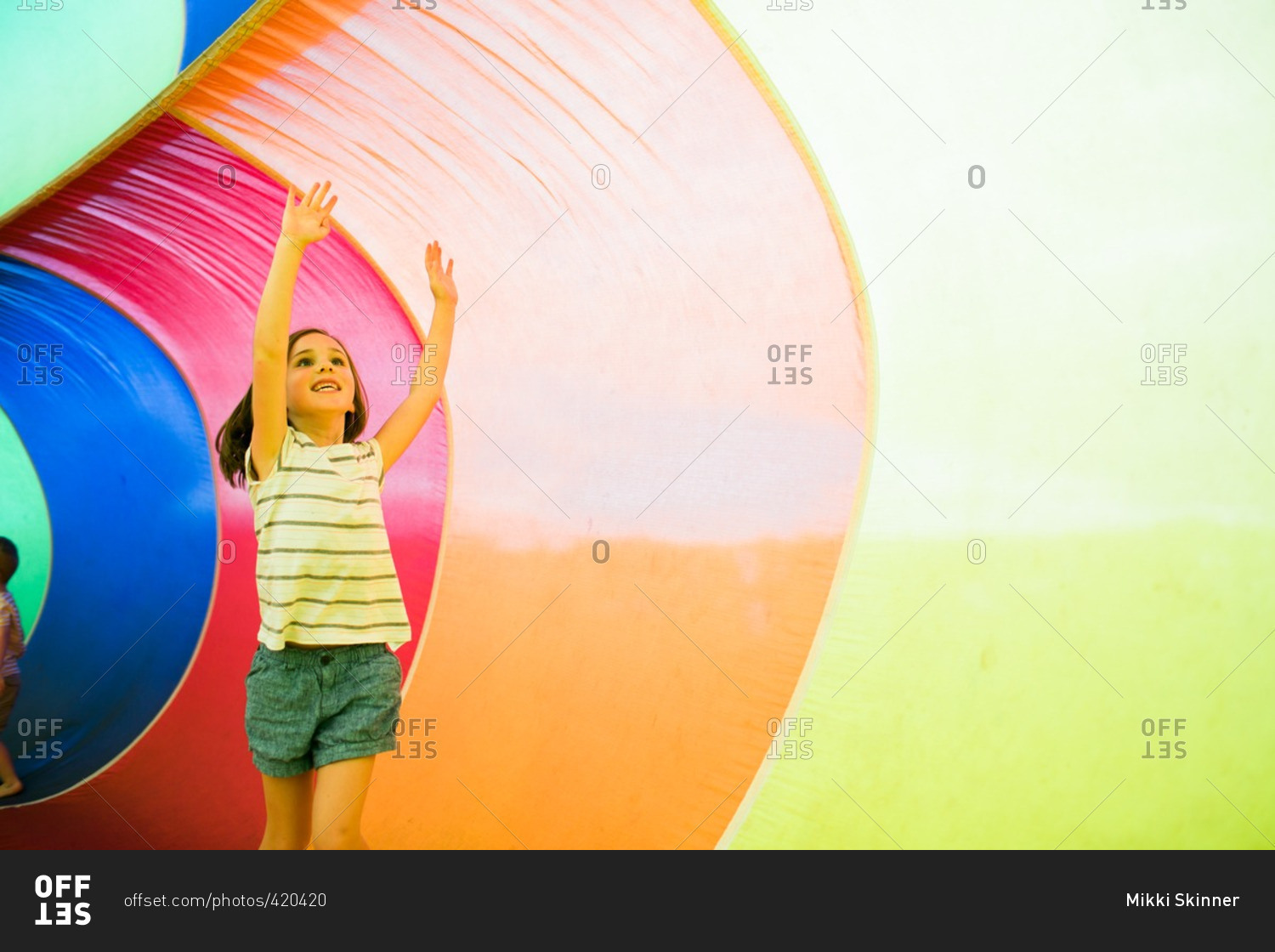 Girl playing inside an inflatable rainbow parachute