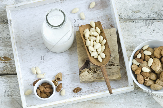 Glass bottle of homemade almond milk, whole and cracked almonds