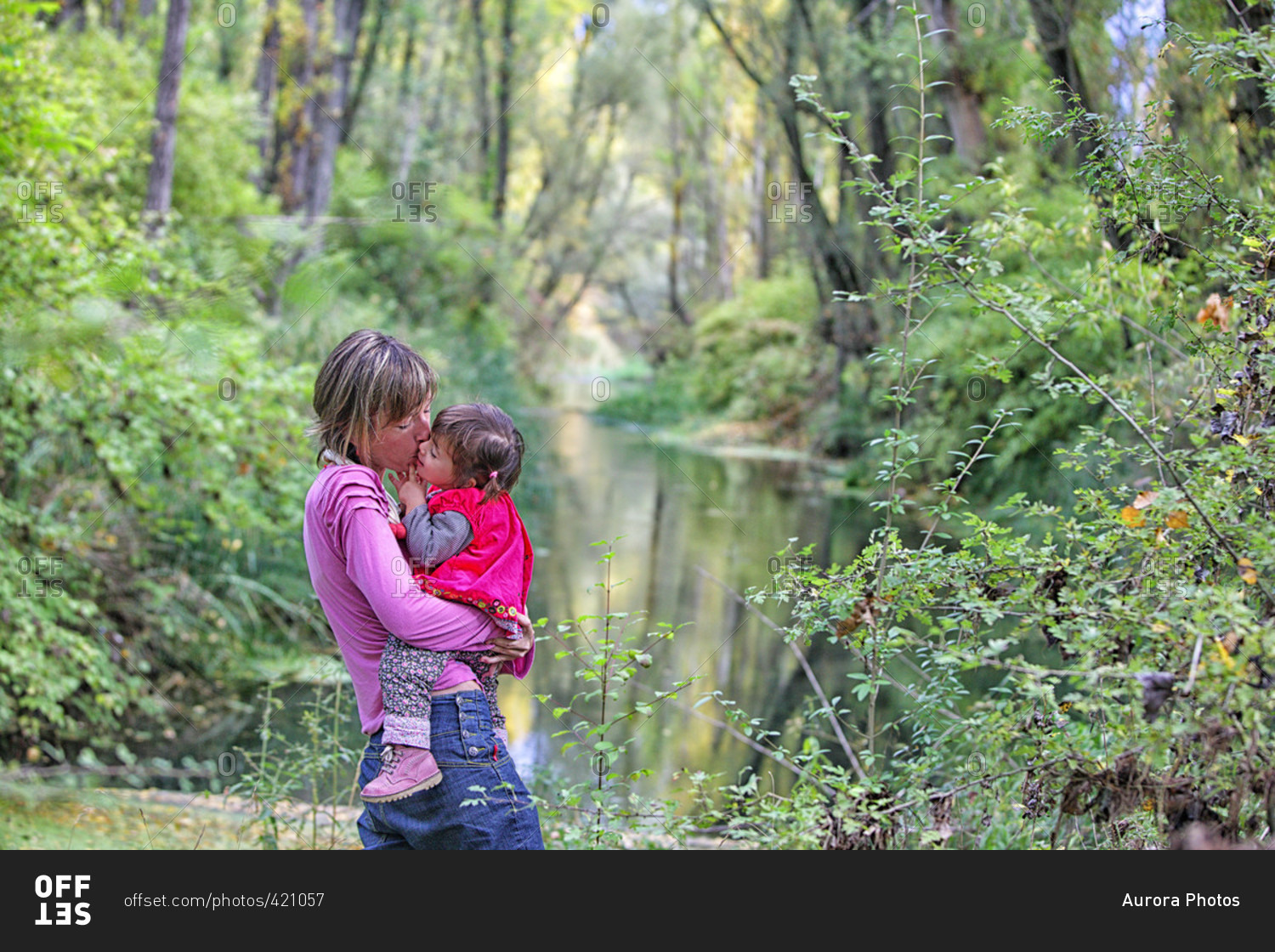 Mother Kissing Daughter On Chick In Forest Of Poplars And Pines