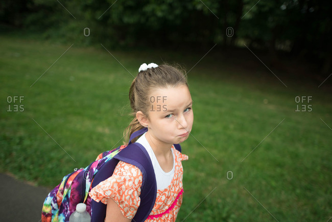 Girl in backpack making a sad face stock photo - OFFSET