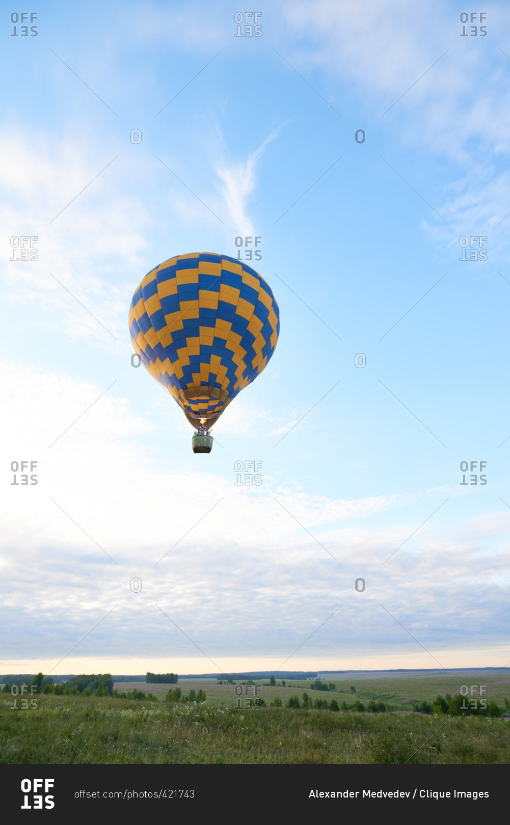 Single hot air balloon floating over the field