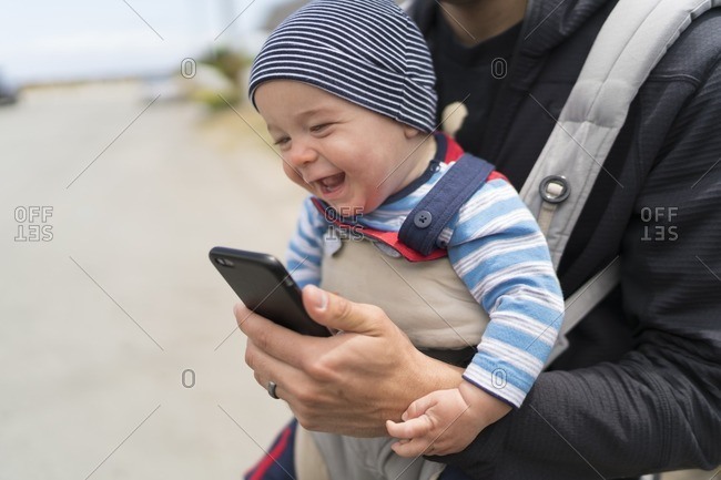 7 month old baby boy laughing and playing with his father's smartphone