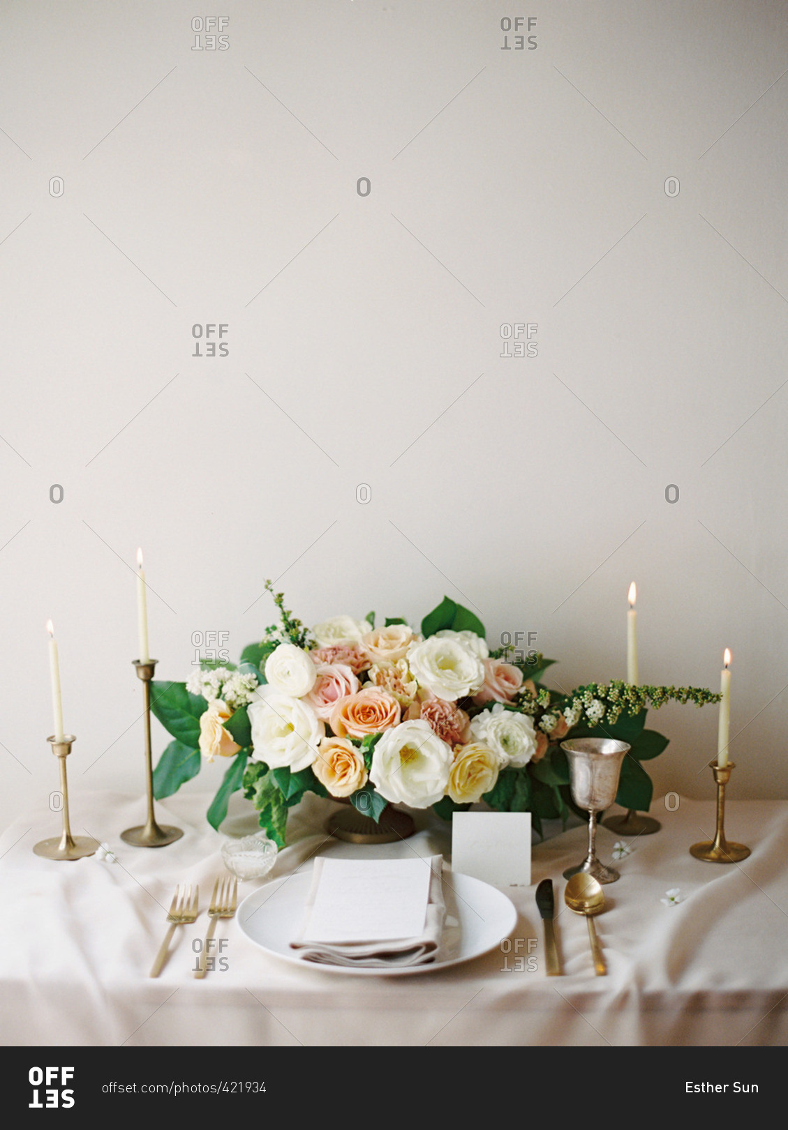 A table set with a bouquet of flowers, candles, plate and silverware