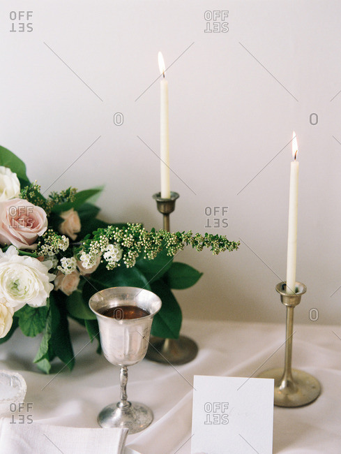 A table set with candles, card, goblet, and a bouquet of flowers