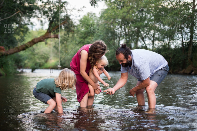 Family picking rocks from bottom of a river stock photo - OFFSET