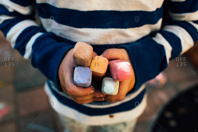Child's hands holding colorful sidewalk chalk