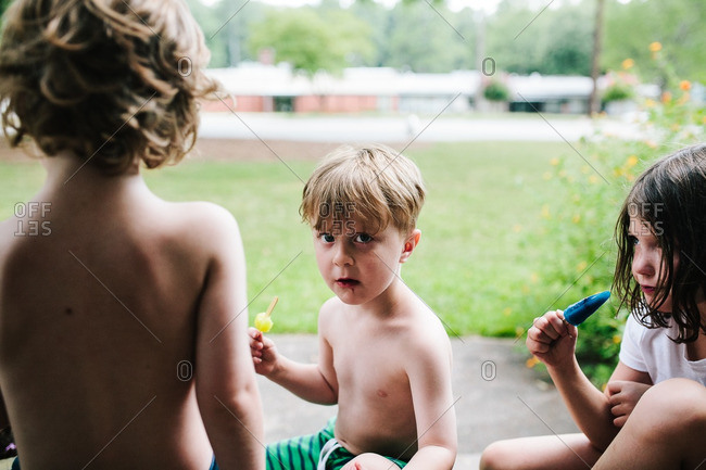 Children sitting outside eating popsicles