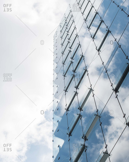Building with glass panels reflecting cloudy sky
