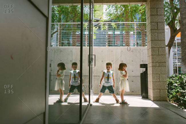 Toddler boy and girl stand outside modern building
