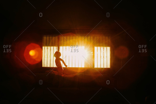 Child silhouetted on couch while playing in living room