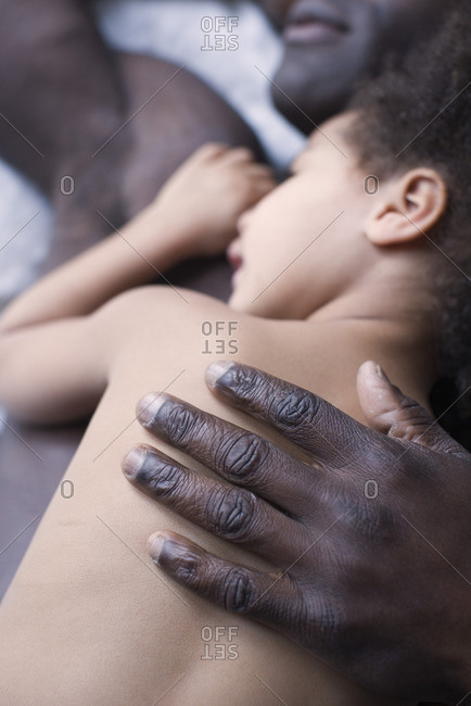 Little girl lying on top of father, focus on father's hand
