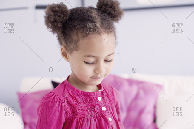 Portrait of toddler girl with hair buns in front of curtains stock photo -  OFFSET