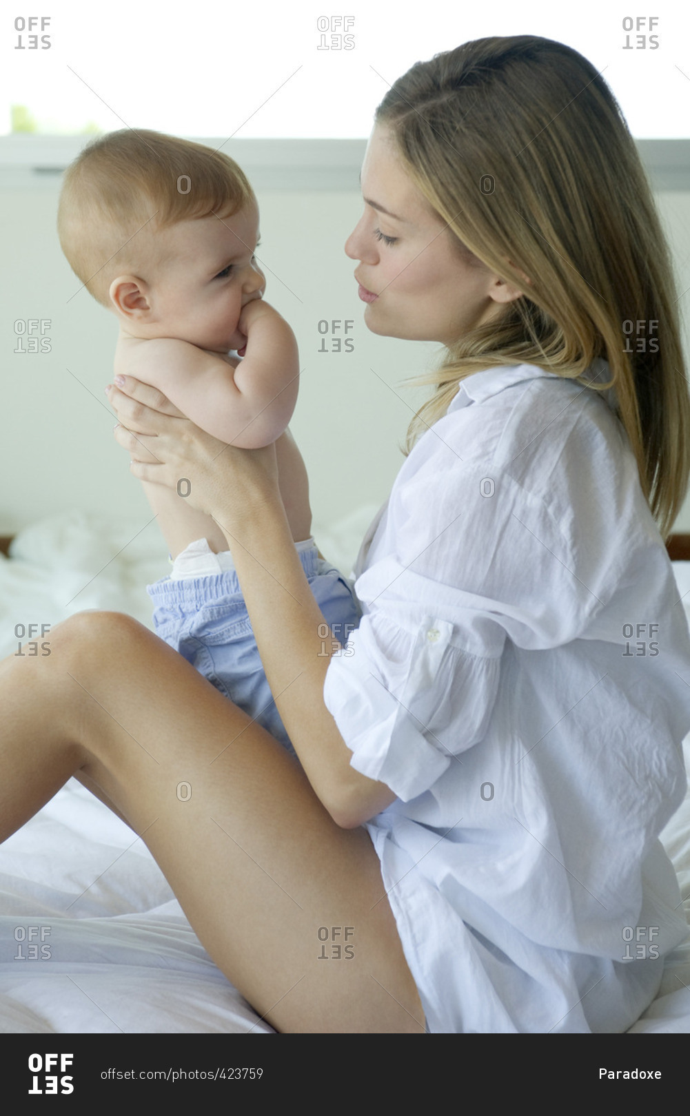 Mother sitting on bed, holding baby on lap