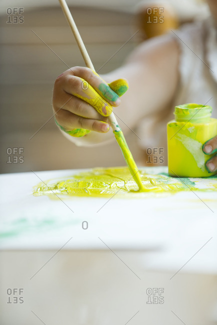 Child painting with paintbrush, cropped