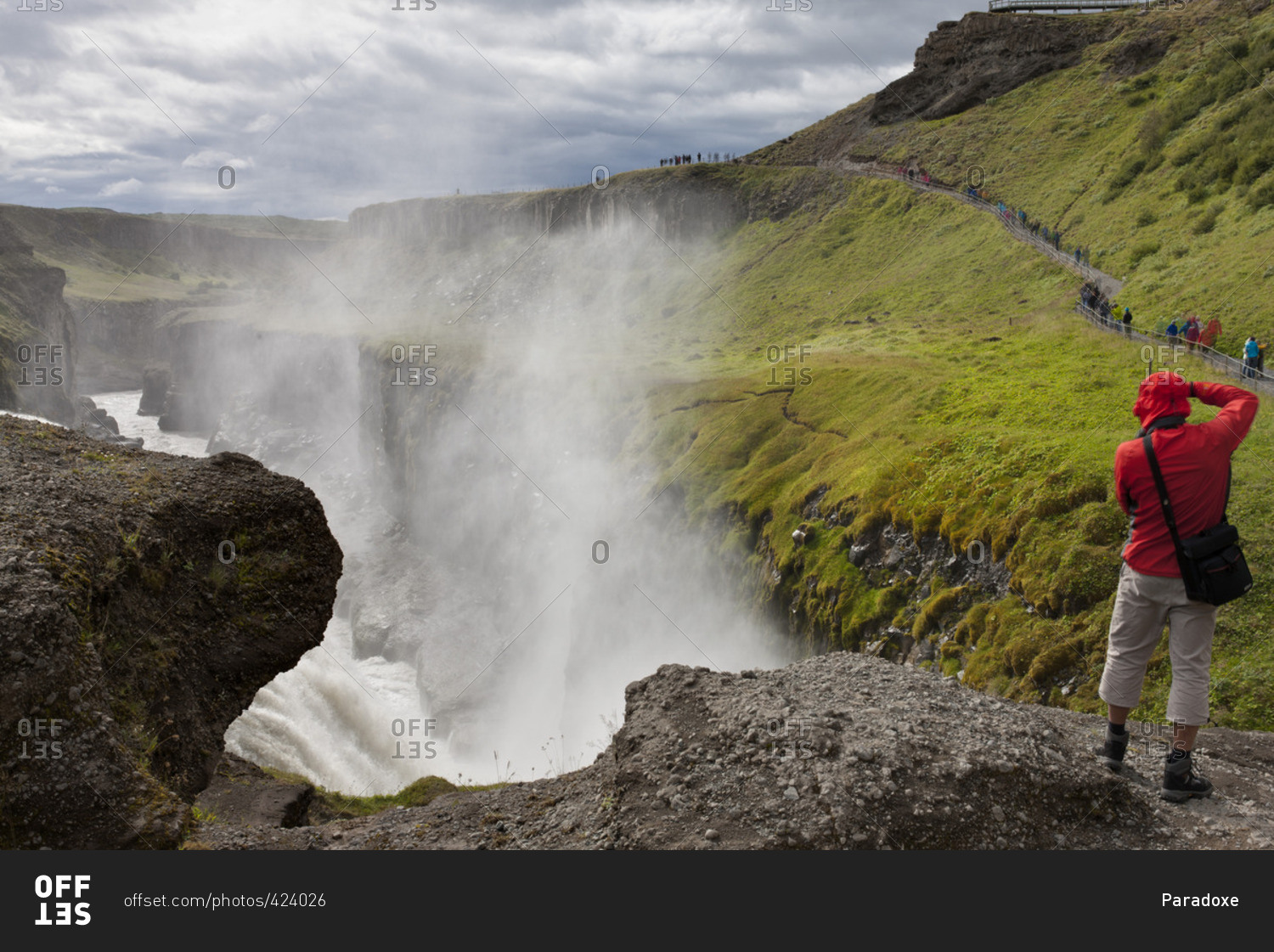 Tourist standing at edge of Gullfoss waterfall, Iceland