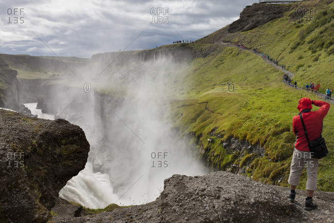 Tourist standing at edge of Gullfoss waterfall, Iceland