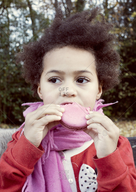 Little girl eating macaroon, portrait
