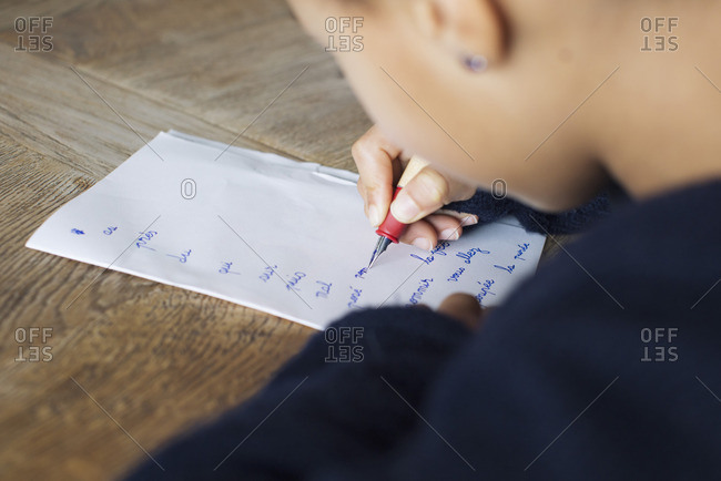 Girl writing in cursive on paper, cropped