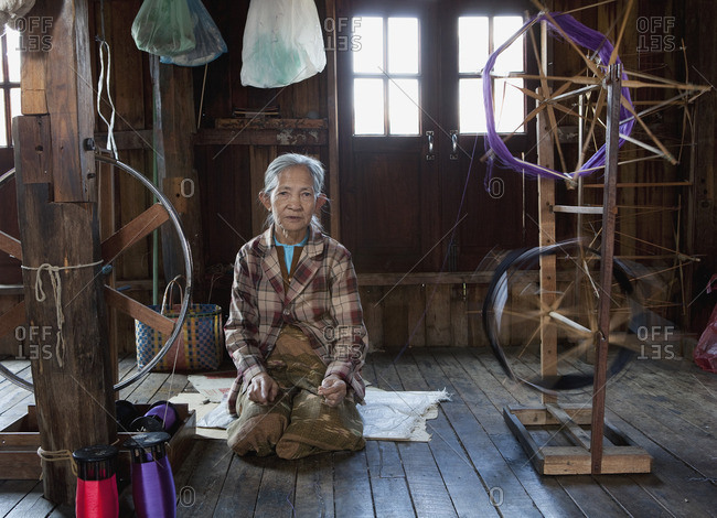 Asian woman sitting near loom