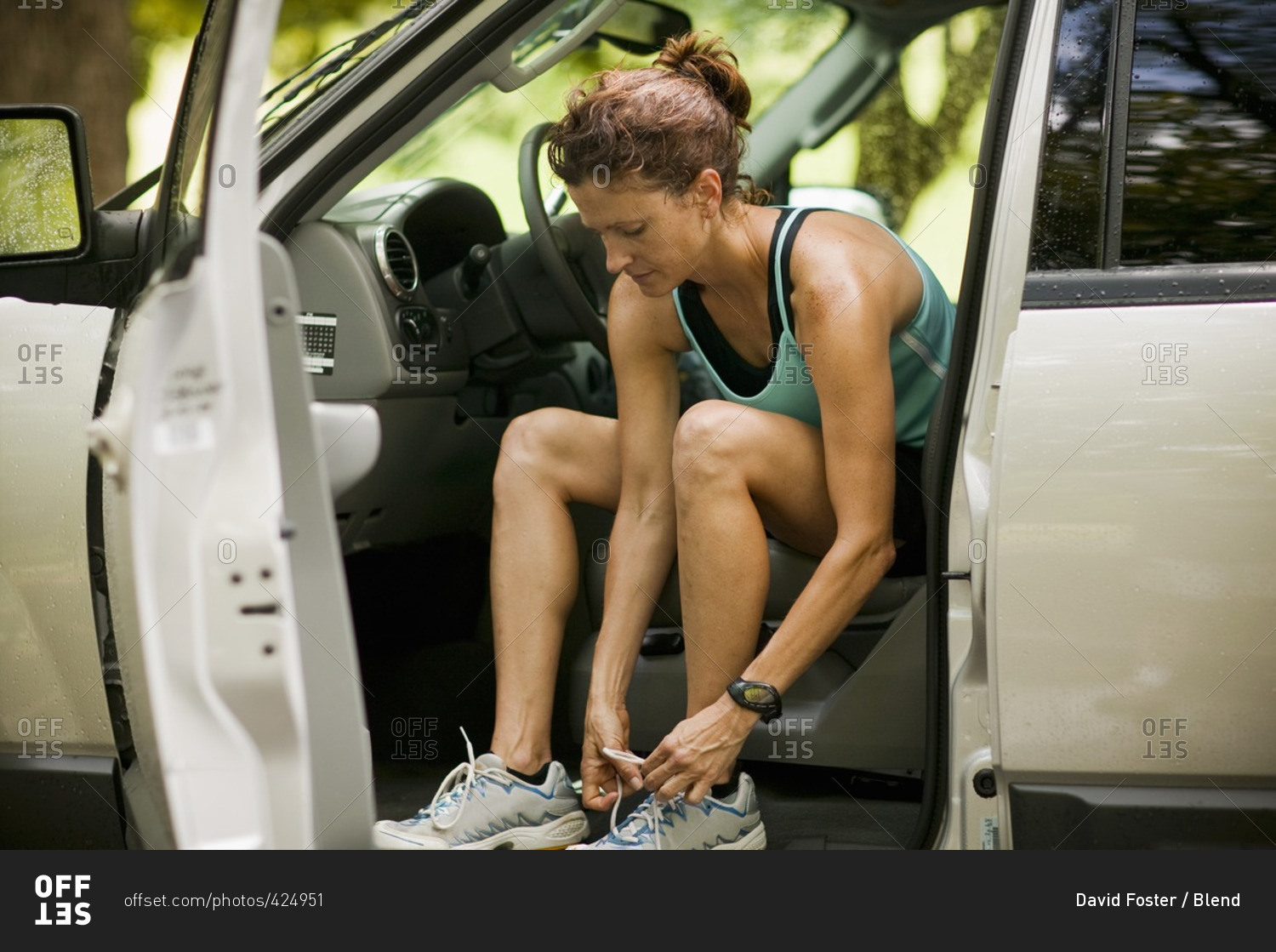 Runner sitting in car tying shoes