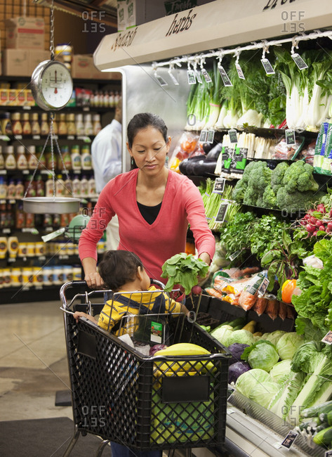 Asian mother and son shopping for fresh vegetables