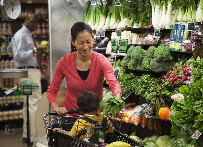 Asian mother and son shopping for fresh vegetables